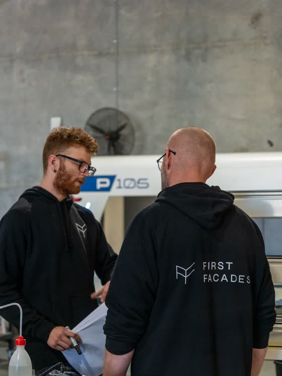 Two First Facades team members talking in their glazing factory