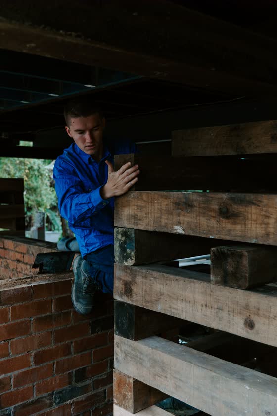 Builder in a blue shirt working under a raised house